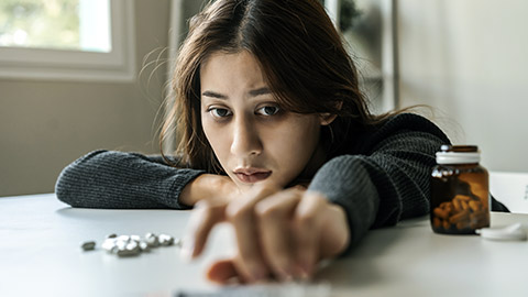 woman reaching for drugs on the table