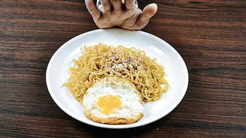 hand refuses noodle and eggs