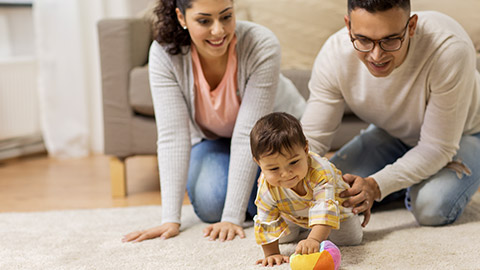 happy mother, father and baby daugter playing with ball at home