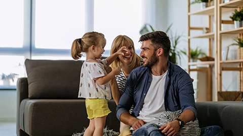 Cheerful family of three playing together at home