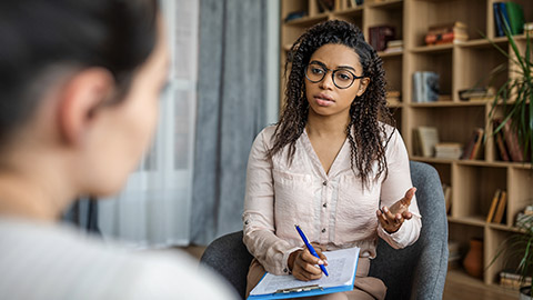 sychologist in glasses talking with patient in office clinic