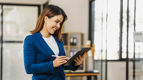 woman in formal suit smiles while checking something on her clipboard