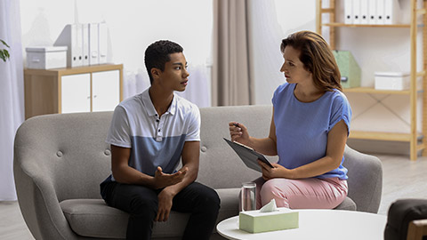 Psychotherapist working with African-American teenage boy in office