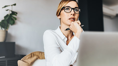 pensive looking woman staring away from laptop screen