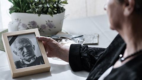 woman looking at a dead photo of husband