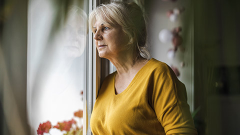 Worried elderly woman looking in window