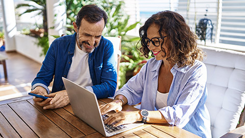 couple smiling confident using laptop and smartphone at home