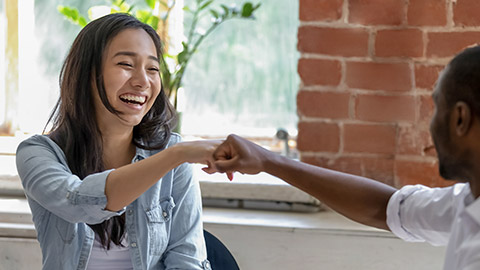 woman with colleague fists bump aving fun together