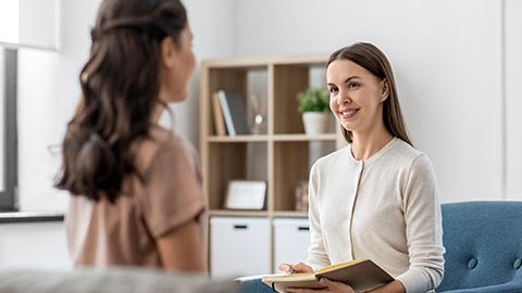 smiling psychologist with notebook and woman patient at psychotherapy session