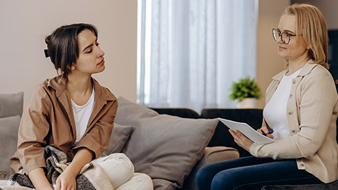 woman is sitting on the couch talking to a specialist in her office