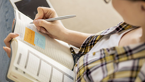 Close-up of busy young woman making notes