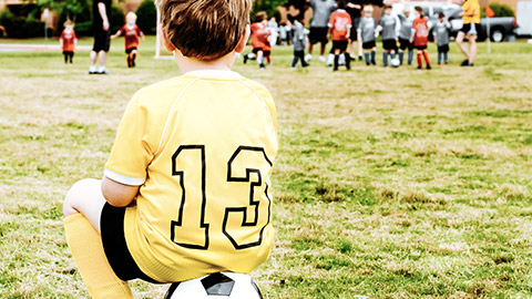 Boy in uniform watches soccer game