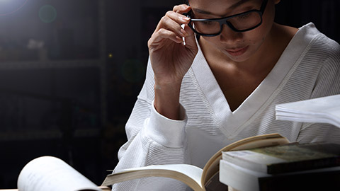 Asian Girl in white shirt reading many textbooks on table with many high stacking of local and international Books Journal Report