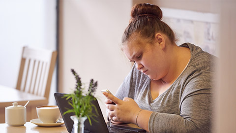 overweight teenager sitting in a bright coffee shop to work