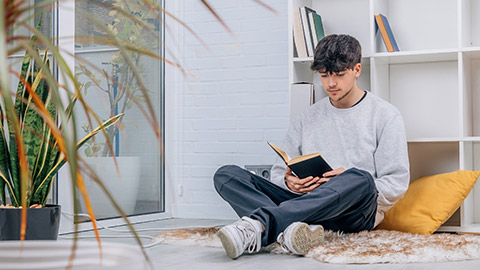 teenage student at home or library reading a book