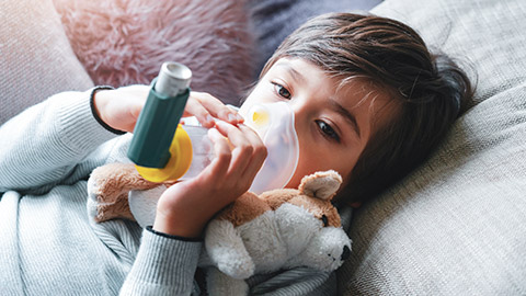 A young child using an asthma inhaler