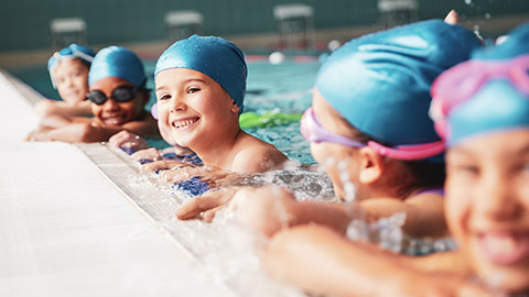 A group of young kids doing swimming lessons