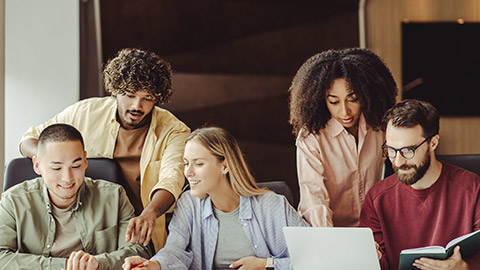 Group of smiling multiracial university students using laptop studying together