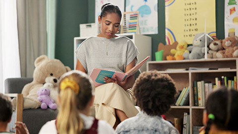 Kindergarten, teacher and reading a story to children in montessori school,