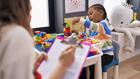 African american boy playing with construction blocks having psychotherapy at kindergarten