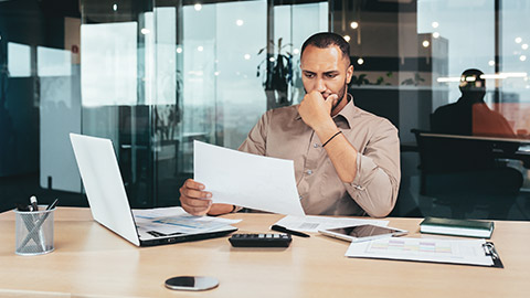 An accountant reading documents at a desk in a modern office