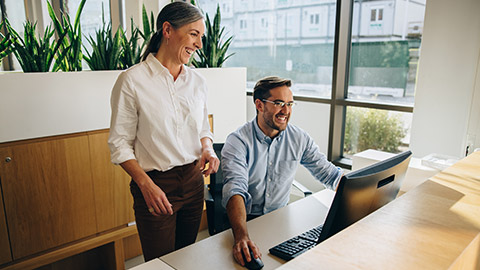 2 coworkers discussing a business report on a computer screen