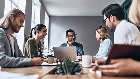 Group of young modern people in smart casual wear discussing business while working in the creative office