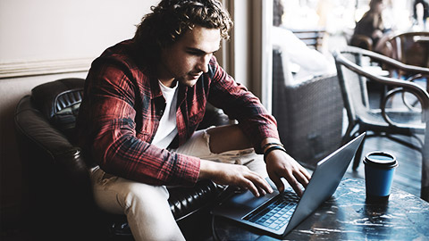 A visual artist researching in a cafe with their laptop