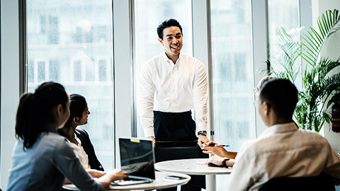 A person speaking with colleagues in a meeting