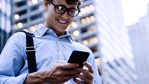 Man with eyeglass smiling while looking at phone