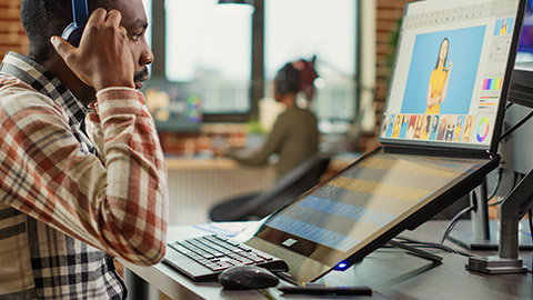 Graphic designer expert editing pictures on touchscreen monitor, using tablet and stylus pen in studio office