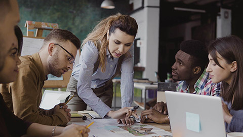 Brunette female team leader talking with mixed race group of people