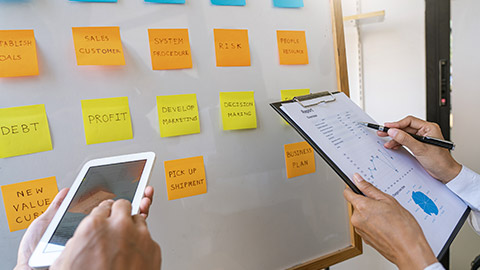 workers posting with sticky notes stickers reminders creative brainstorming at board