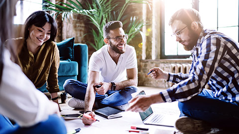 Group of millenials sitting on the floor, working on a project