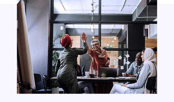 Cheerful women doing high five during business meeting