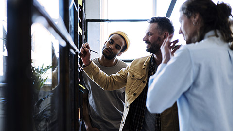 3 men discussing a project on wall