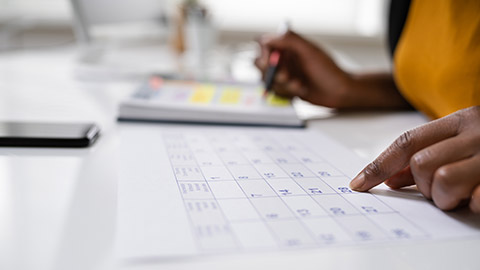 A close view of a planner checking a schedule on a calendar