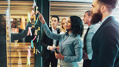 A group of accountants discussing accounting software systems with sticky notes on a glass wall