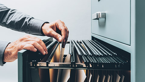 A close view of a person putting files into a filing cabinet