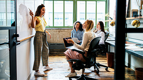 An entrepreneur presenting to their business' team members in a modern office