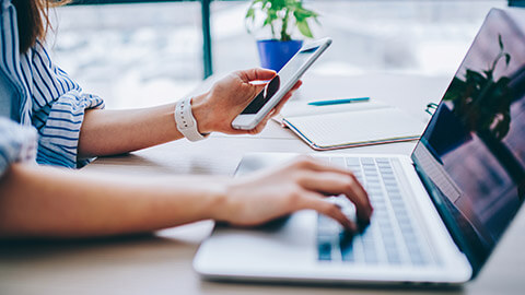 A close view of a person entering security information from a phone onto a laptop