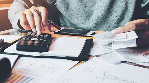 An accountant adding up invoices on a calculator