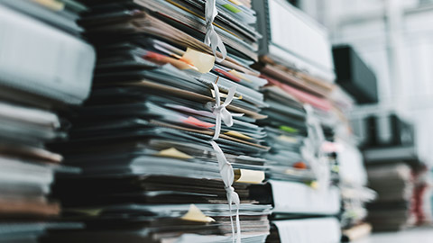 A stack of business files on a table waiting to be placed in a filing cabinet