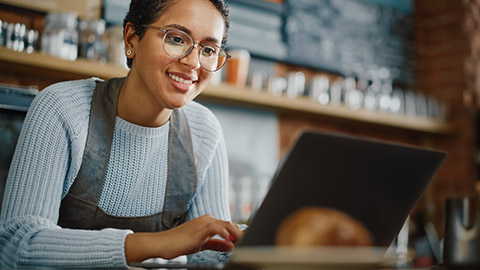 A small business owner entering financial details on a laptop