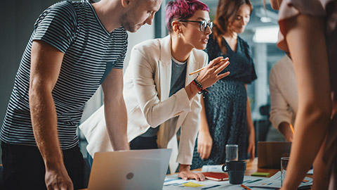 A group of work colleagues standing around a table discussing communication requirements