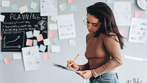 A business owner talking on the phone while writing notes on paper