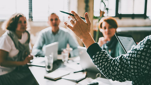 Over the shoulder view of a person presenting to a group of coworkers in an office