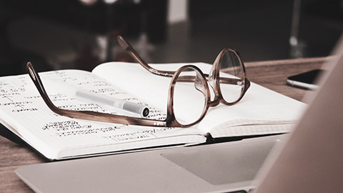 A close view of a pen and a pair of glasses sitting on a notebook