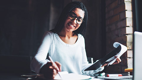 A business professional sitting at a desk working on financial software on a laptop