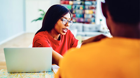 A manager delivering verbal feedback to one of their team members in a one-on-one meeting